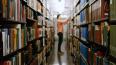 A person pulling a book off a shelf in a library